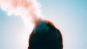 Person vaping with Zero Nic Vape, with vapor rising into the clear sky.