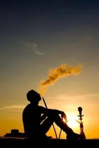 Silhouette of a person smoking at sunset, symbolizing the switch from smoking to a cleaner alternative.